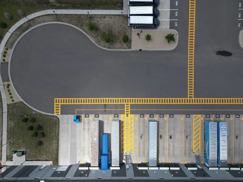 Aerial top-down view of a warehouse loading dock with several trailers backed into numbered dock doors