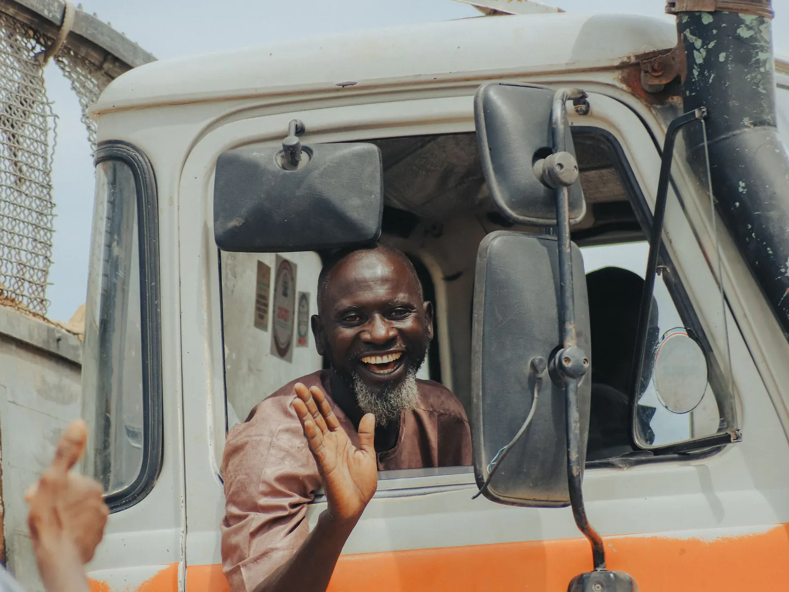 Smiling truck driver waving from the window of his truck cab